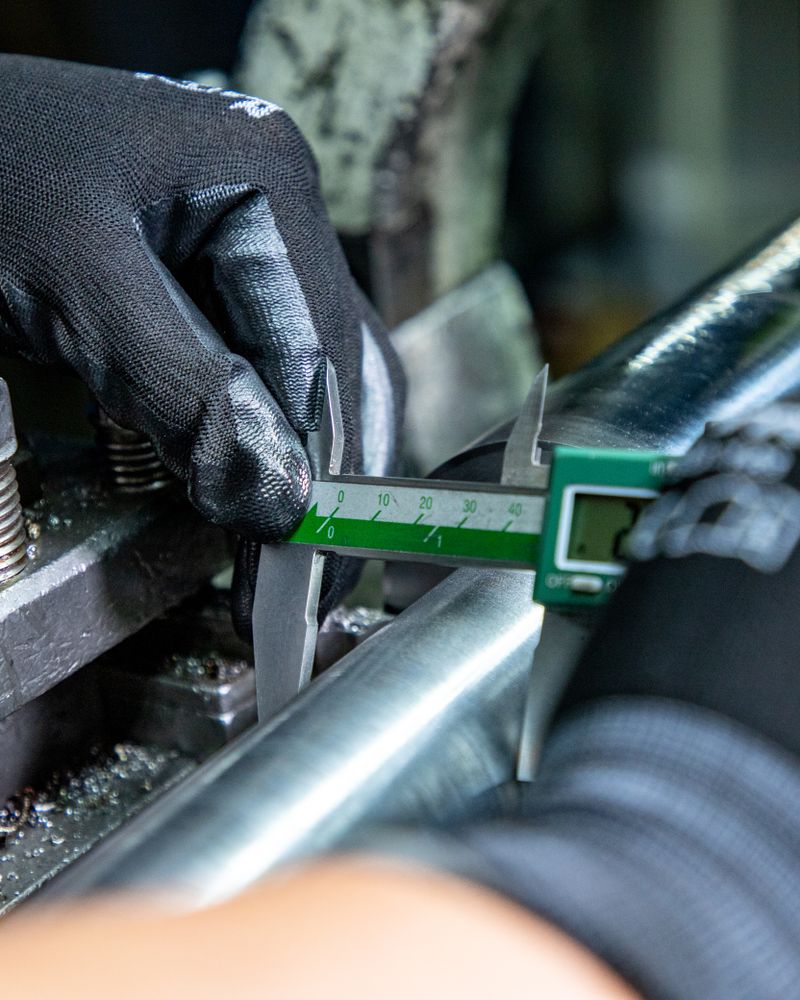 Digital caliper precision inspection of a machined metal part at UD Manufacturing in central Arkansas